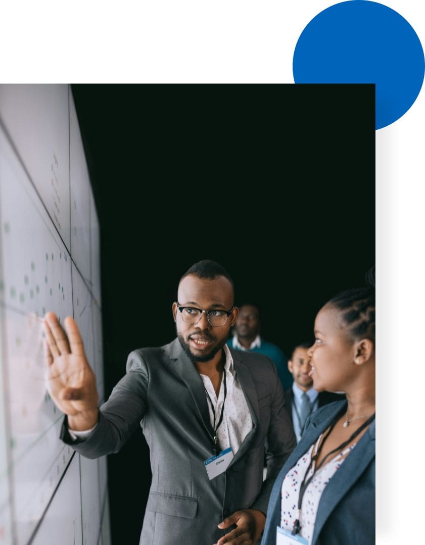 A man and woman are standing in front of a whiteboard.