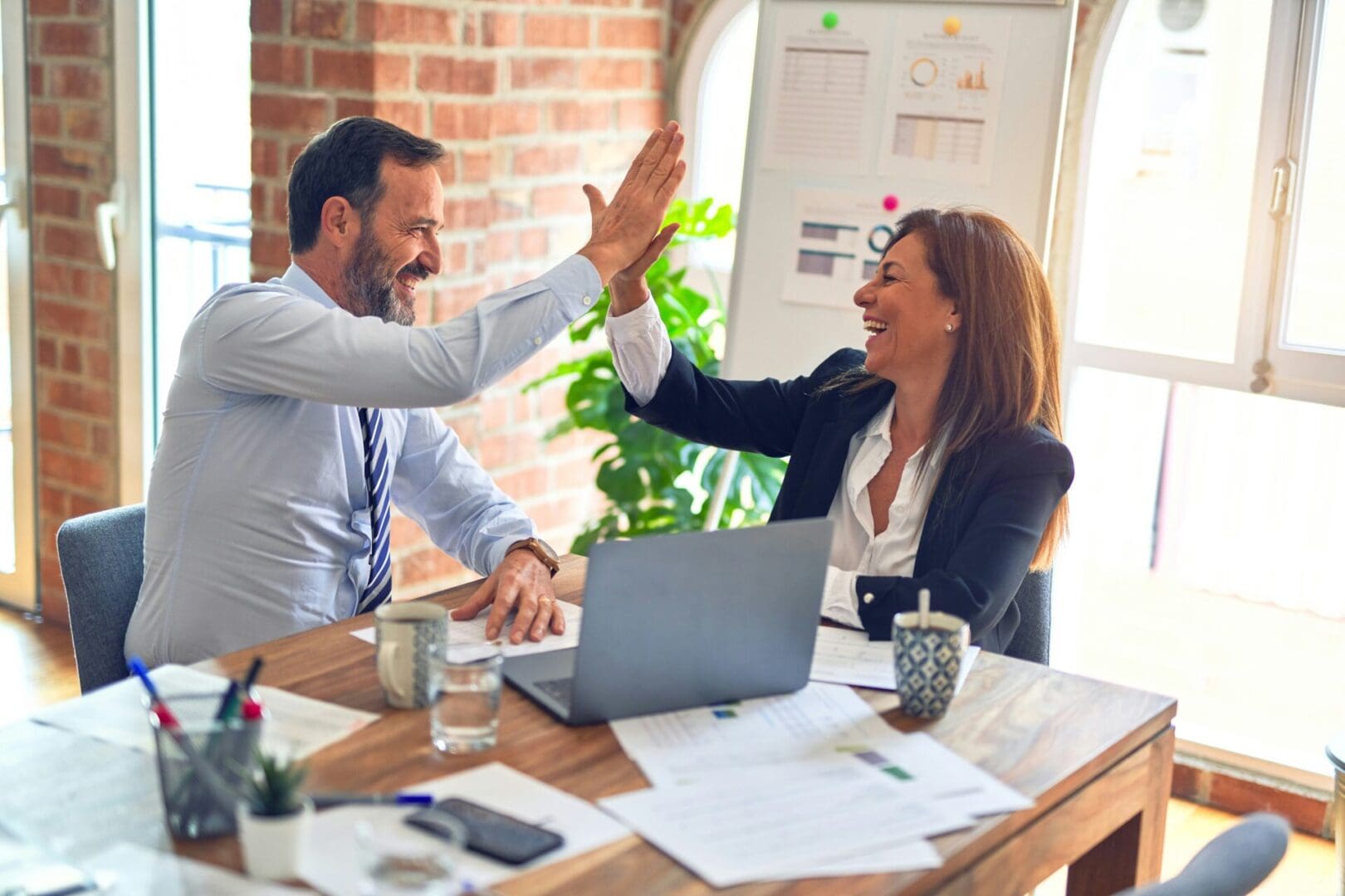 Two people giving each other a high five at the table